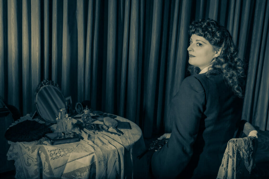 Themed Photo-Shoot:  Film Noir Photography with Welshot - Black and White Photo of Woman sitting at a bedroom table getting ready to go out