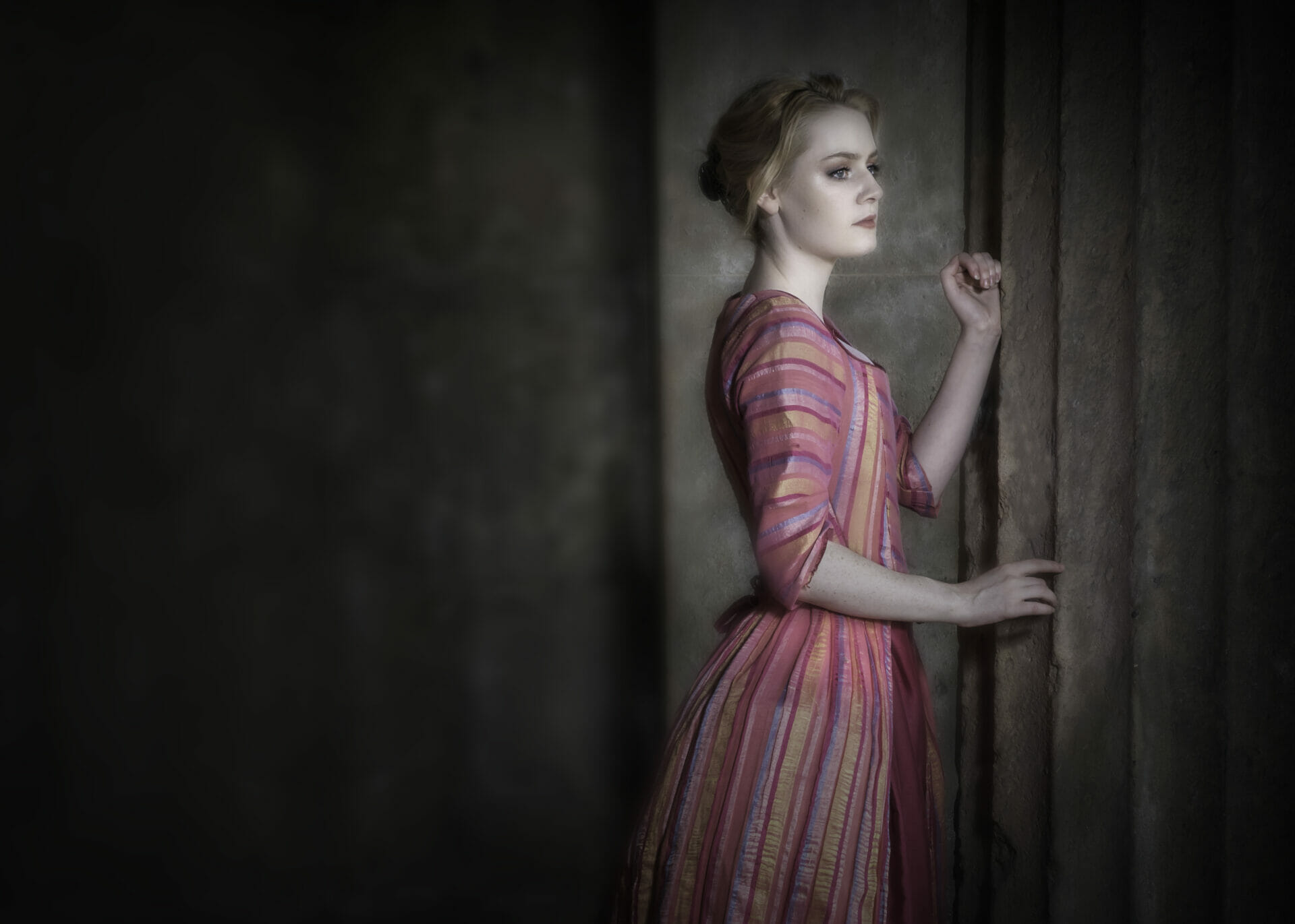 Photography & Period Costumes on Location at The Bulkeley Hotel - Photo of a female models wearing a period costume leaning on a pillar and looking into the distance