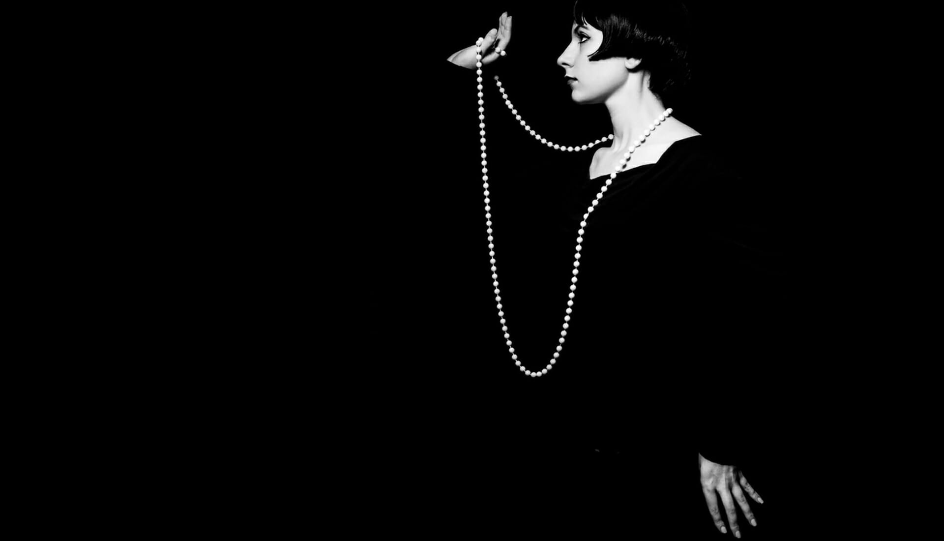 Photo of a Girl wearing black on a black background holding some white pearls - Studio Mains Flash Photography - Chester Photographic Academy Evening