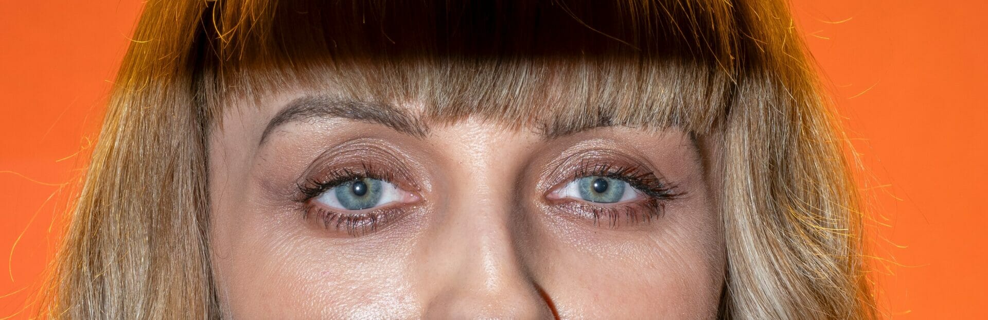 Female Model showing eyes only on an orange backdrop